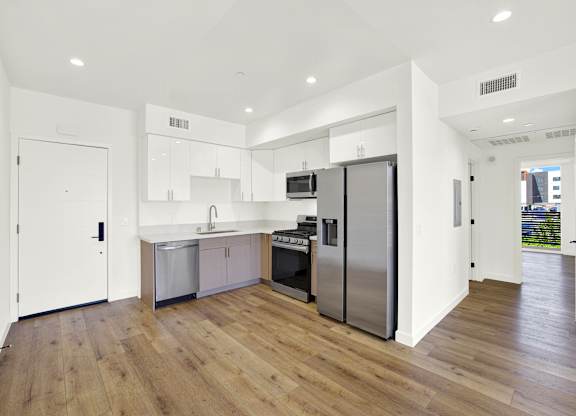 A modern kitchen with wooden floors and stainless steel appliances.