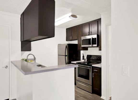 A kitchen with a white counter top and stainless steel appliances at Monterra Ridge Apartments, Canyon Country