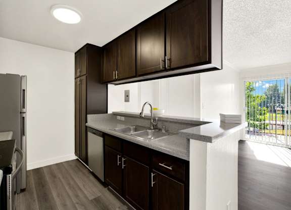 A kitchen with dark wood cabinets and a white sink at Monterra Ridge Apartments, Canyon Country