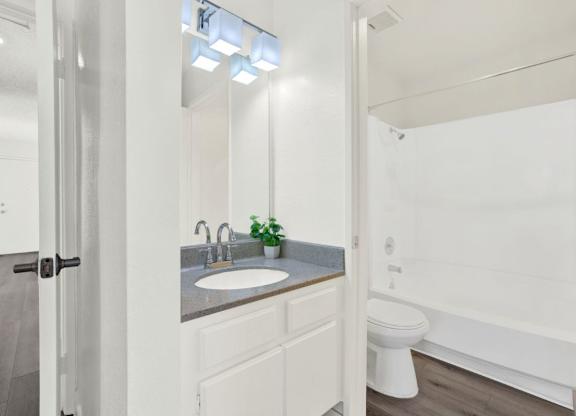 A white bathroom with a sink, toilet, and bathtub at Monterra Ridge Apartments, Canyon Country