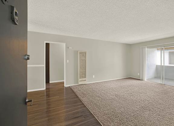 A room with a carpeted floor and a door on the left at The Square in Downey, CA, 90242
