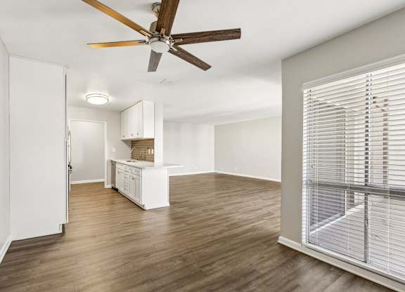 A room with a ceiling fan and wooden flooring.