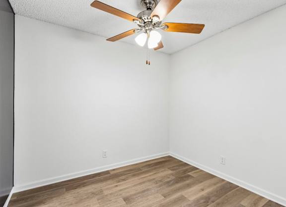 A room with a ceiling fan and wooden flooring.
