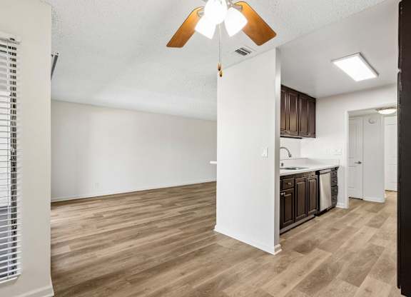 A kitchen area with wooden flooring and a white wall.