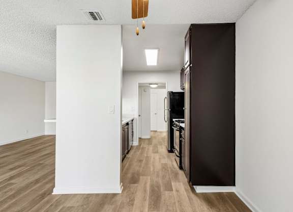 A kitchen with a white wall and a brown refrigerator.