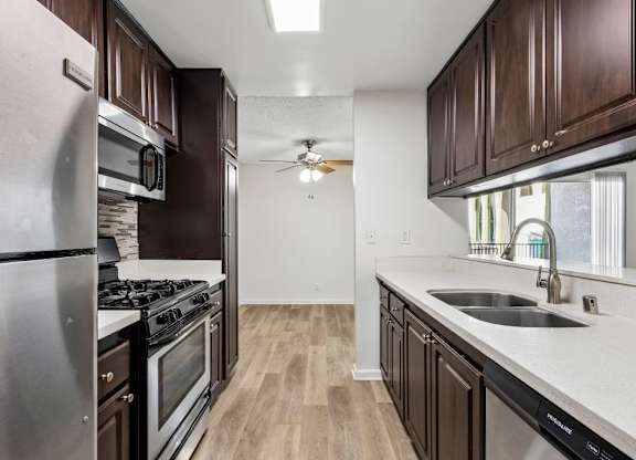 A kitchen with dark wood cabinets and stainless steel appliances.
