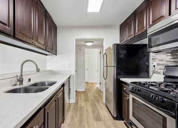A kitchen with dark brown cabinets and a black refrigerator.