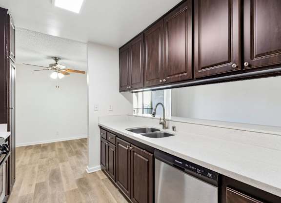 A kitchen with brown cabinets and a stainless steel dishwasher.