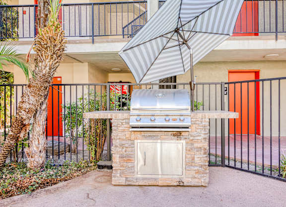 A patio with a grill and a tree.