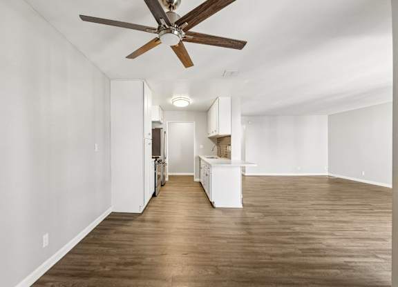 A room with a ceiling fan and wooden flooring.
