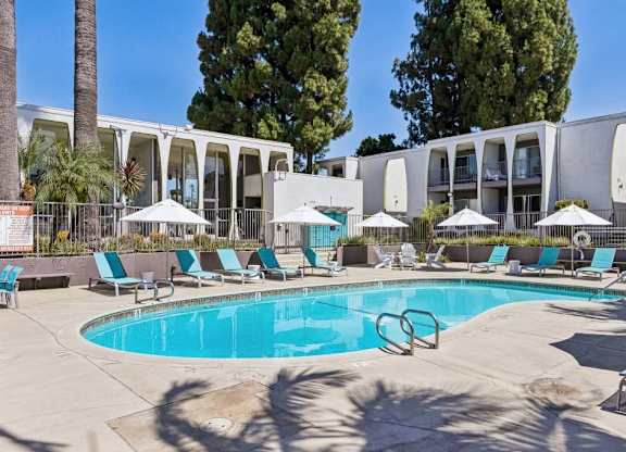 A swimming pool surrounded by lounge chairs and umbrellas.
