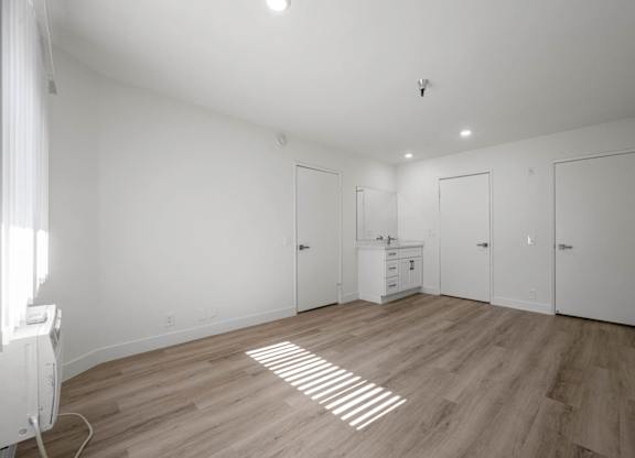A room with wooden floors and white walls, with a radiator on the left side.