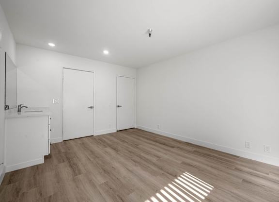 A room with a sink and wooden floors.