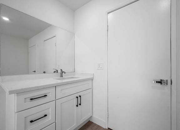 A white bathroom with a sink and mirror.