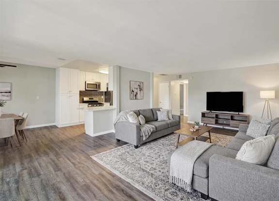 Spacious living room with gray sofas and wood flooring at Parc @ 5 Apartments, Downey, CA