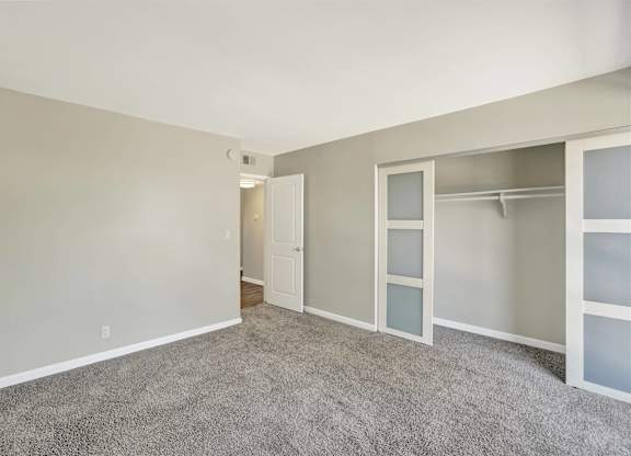 Bedroom with walk-in closet and carpeted flooring at Parc @ 5 Apartments, Downey