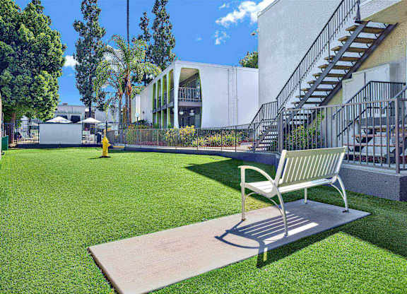 Outdoor courtyard with bench and artificial turf lawn at Parc @ 5 Apartments, Downey, CA