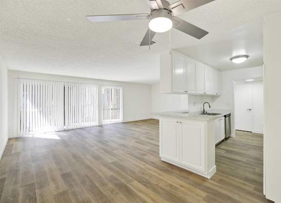 Open living area with white kitchen and vinyl plank flooring at Parc @ 5 Apartments, California, 90240
