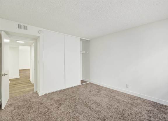 Carpeted bedroom with sliding closet doors at Parc @ 5 Apartments, Downey, CA