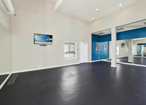 Empty fitness studio with mirrored walls and dark flooring at Parc @ 5 Apartments, Downey, CA 90240