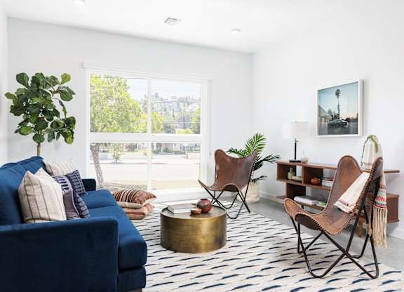 A living room with a blue couch and a chair with a blanket on it.