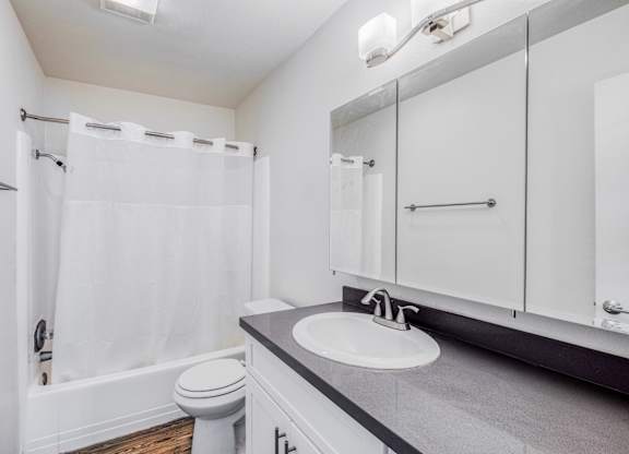 A white bathroom with a toilet, sink, and shower.