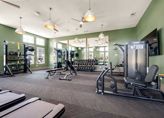A gym with a variety of equipment including treadmills, weights, and exercise machines.