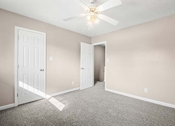 A room with a ceiling fan and two doors.