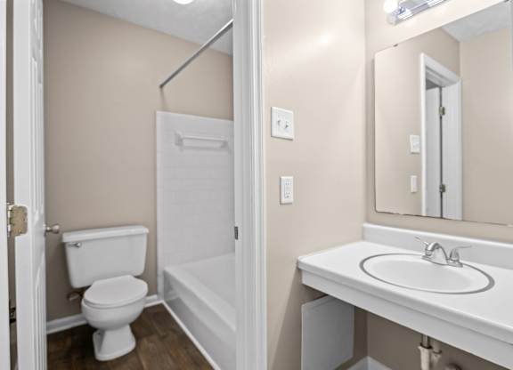 A white toilet is in a small bathroom with a white sink.