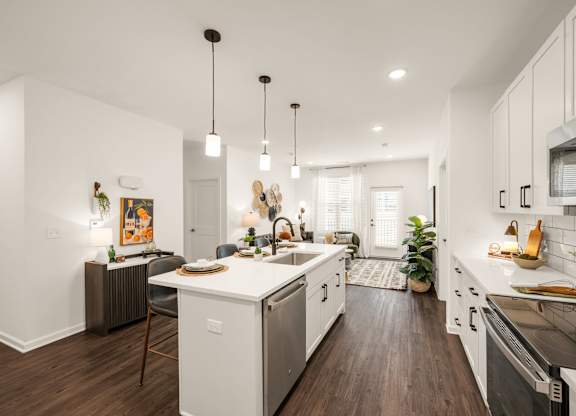 A modern kitchen with white cabinets and a wooden floor.