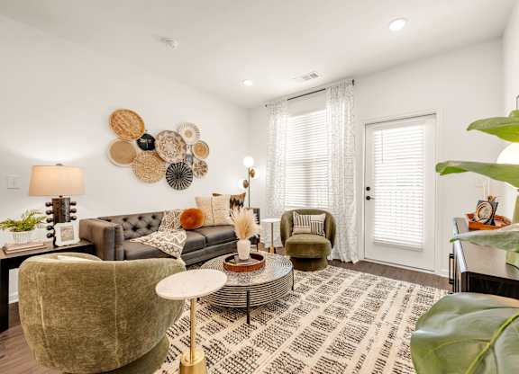 A living room with a grey couch, a green armchair, a coffee table, and a large decorative wall piece.
