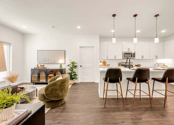 A modern kitchen with white cabinets and a dark wood floor.