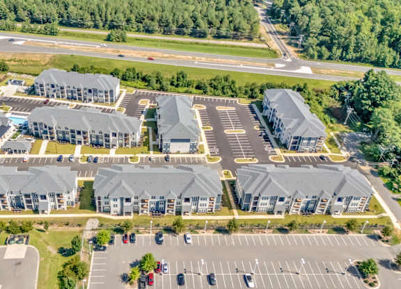 A large, modern building complex with a parking lot in front.
