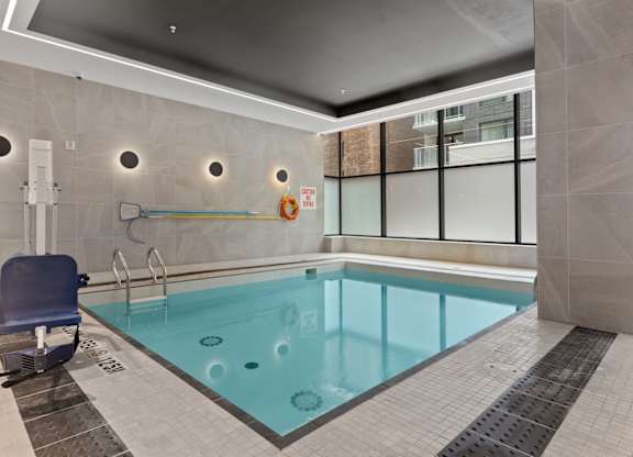 A small indoor pool with a blue chair.