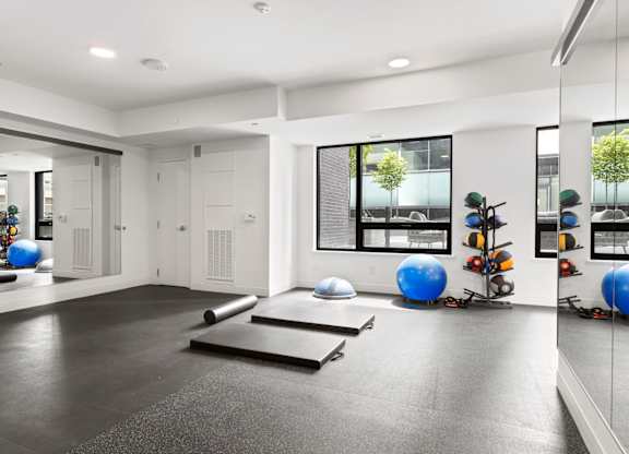 A spacious room with exercise equipment and mirrors on the wall.