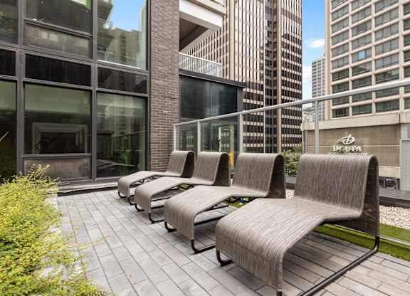 A row of grey couches are lined up on a patio.