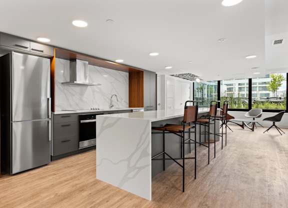 A modern kitchen with a refrigerator, sink, and bar area.