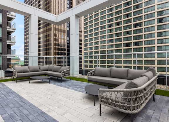 A patio with a white couch and a black table.