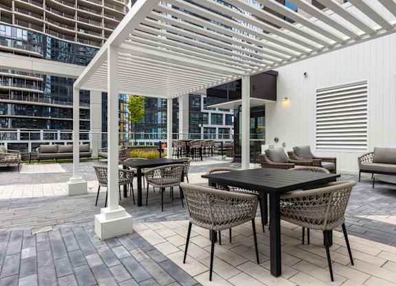 A patio with a table and chairs under a white pergola.