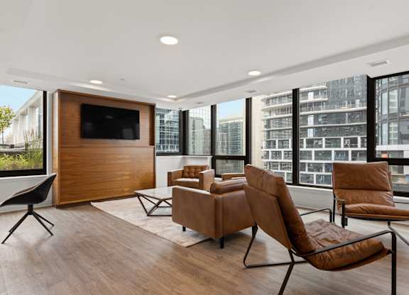 A modern living room with brown leather chairs and a wooden entertainment center.