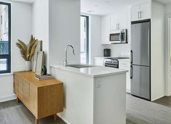 a kitchen with a white counter top and a stainless steel refrigerator