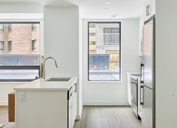 an empty kitchen with a large window and a sink and a refrigerator
