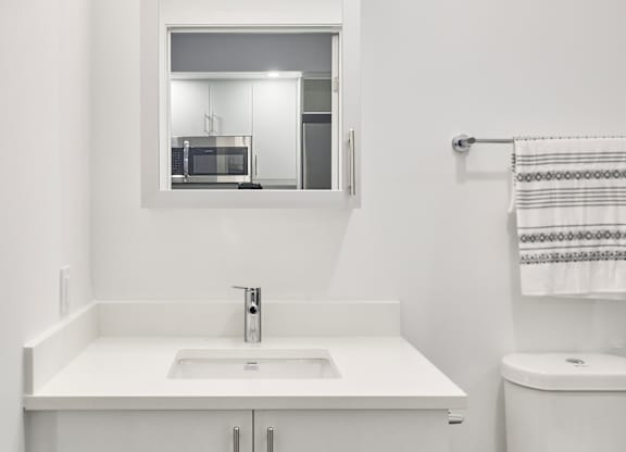 a white bathroom with a sink toilet and mirror
