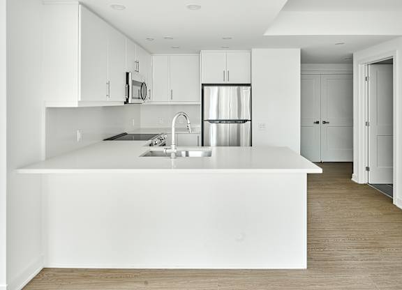 a large white kitchen with a white counter top and a white