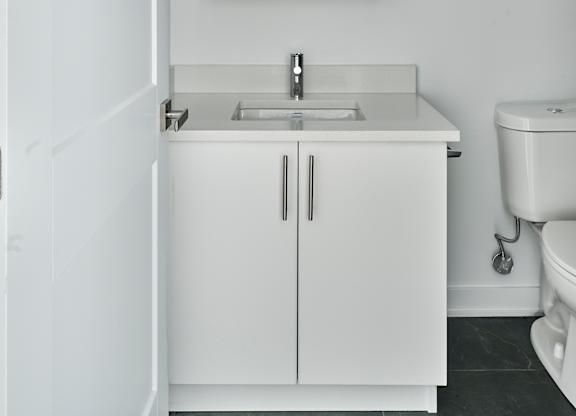 a white bathroom with a sink and mirror and a toilet