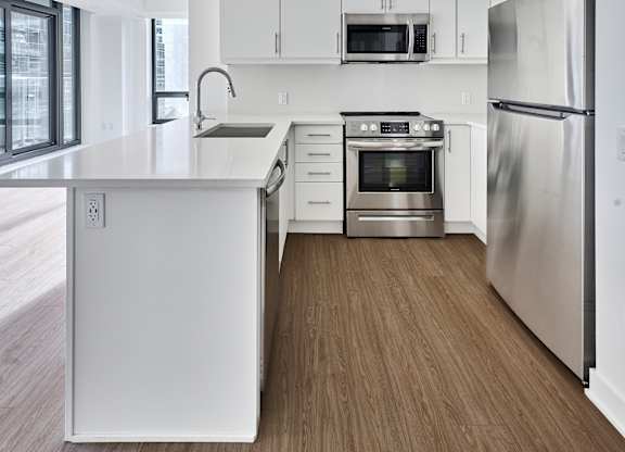 an empty kitchen with white cabinets and stainless steel appliances