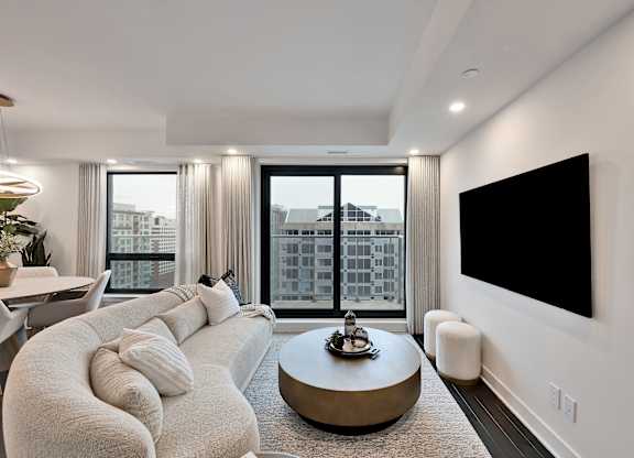 A modern living room with a large window and a flat screen TV mounted on the wall.
