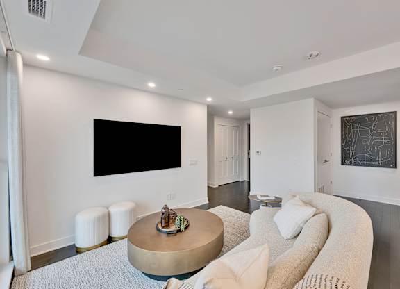 A modern living room with a large couch and a flat screen TV mounted on the wall.