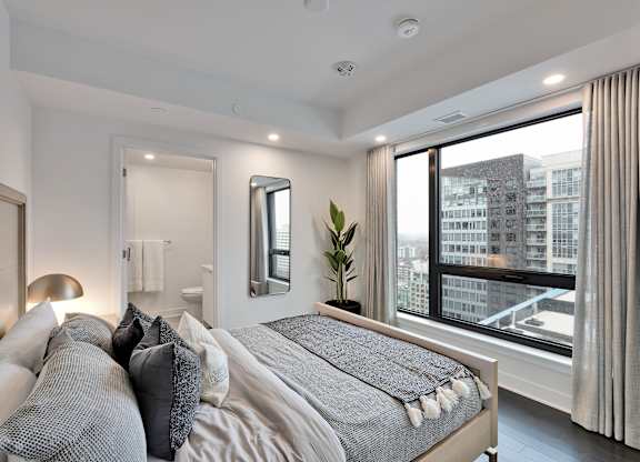 A bedroom with a large bed and a view of the city.