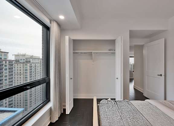 A bedroom with a large bed and a view of a cityscape through a window.